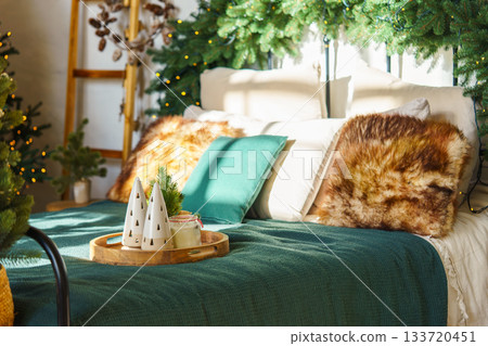 Cozy Christmas bedroom with green blanket and decorative pillows with festive holiday decorations Cozy Christmas bedroom with green blanket and decorative pillows with festive holiday decorations 133720451