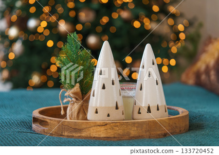 Decorative ceramic Christmas trees and mini pine on wooden tray with warm holiday lights background Decorative ceramic Christmas trees and mini pine on wooden tray with warm holiday lights background 133720452