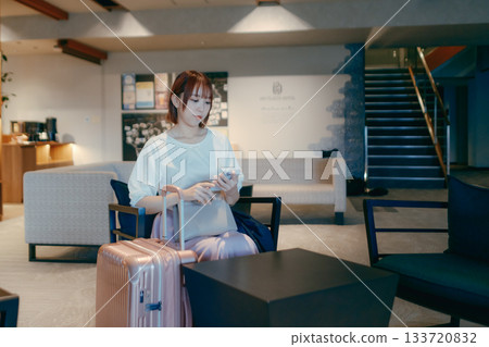 A woman in her twenties working on a computer in a hotel lobby 133720832