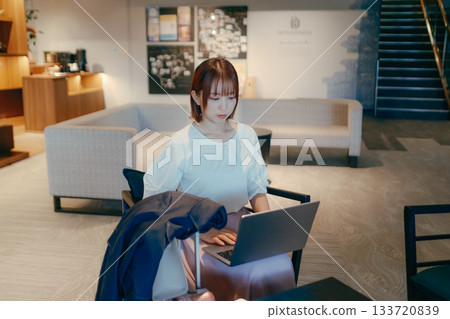 A woman in her twenties working on a computer in a hotel lobby A woman in her twenties working on a computer in a hotel lobby 133720839