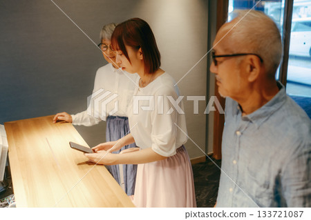 A scene where three parents and children check in at a hotel A scene where three parents and children check in at a hotel 133721087
