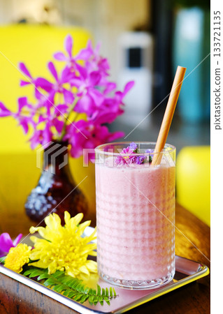 A glass of blueberries smoothie and violet flowers decorated on topping 133721135