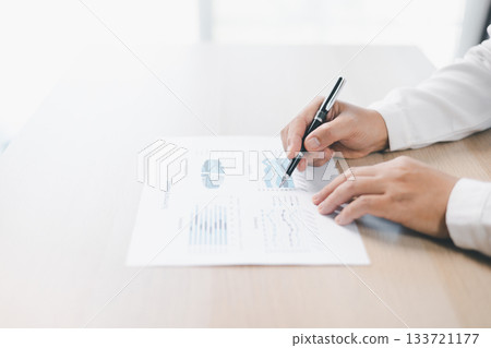 Businessman reviews financial reports, points on chart with pen while analyzing data at office desk working with calculator for accuracy. Concept of accounting, business planning, investment strategy. 133721177