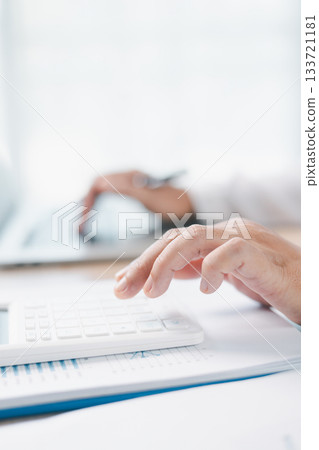 Close up of businesswoman using calculator for financial analysis and accounting on office desk with charts and reports. Concept of business planning, budget calculation and investment strategy. 133721181