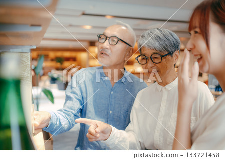 A scene of a family of three choosing souvenirs at a hotel shop 133721458