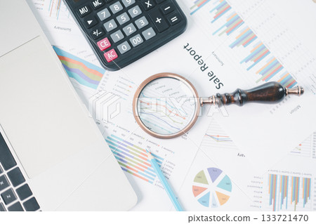 Magnifying glass with calculator and pen on financial reports with charts, graphs at office desk. Concept of business analysis, accounting audit, financial accuracy, transparency, corporate strategy. Magnifying glass with calculator and pen on financial reports with charts, graphs at office desk. Concept of business analysis, accounting audit, financial accuracy, transparency, corporate strategy. 133721470