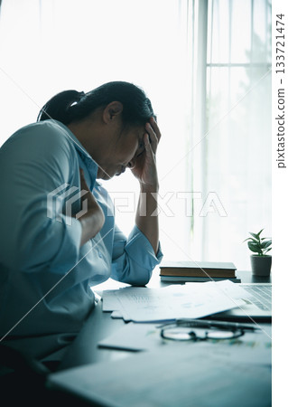 Stressed businesswoman working late at home office, feeling exhausted while reviewing financial documents on laptop. Concept of work stress, burnout, deadline, and overwork. Stressed businesswoman working late at home office, feeling exhausted while reviewing financial documents on laptop. Concept of work stress, burnout, deadline, and overwork. 133721474