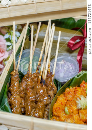 Indonesian lontong, chicken satay with peanut sauce, and spicy potato balado in bamboo hamper Indonesian lontong, chicken satay with peanut sauce, and spicy potato balado in bamboo hamper 133721478