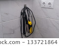 Hair straightener and shoe dryer on tiled bathroom wall. Double socket provides power for these grooming appliances in modern home interior. modern bathroom. 133721864