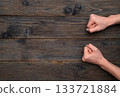 Female hands clenched into fists on rustic wooden background, showing raw strength and determination. Woman's fists resting firmly on wooden table, conveying firm resolve and emotional strength. 133721884