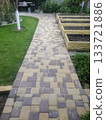 stone paved path has just been laid, with fresh stones neatly arranged in their final pattern. This newly completed pathway shows crisp, clean lines in its pristine installation. stone path in garden. 133721886