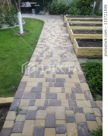 stone paved path has just been laid, with fresh stones neatly arranged in their final pattern. This newly completed pathway shows crisp, clean lines in its pristine installation. stone path in garden. 133721886