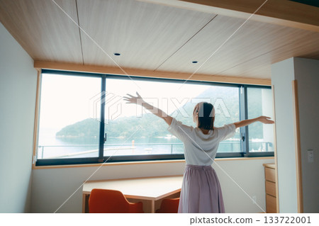 A scene of a woman in her twenties looking at the spectacular view from a hotel room 133722001