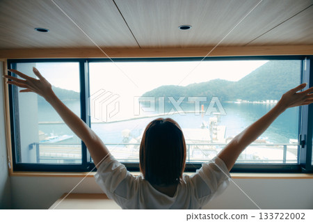 A scene of a woman in her twenties looking at the spectacular view from a hotel room A scene of a woman in her twenties looking at the spectacular view from a hotel room 133722002