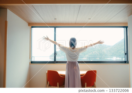 A scene of a woman in her twenties looking at the spectacular view from a hotel room A scene of a woman in her twenties looking at the spectacular view from a hotel room 133722006
