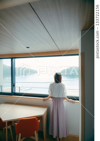 一位二十多歲的女子正望著飯店窗外的景色。 133722156