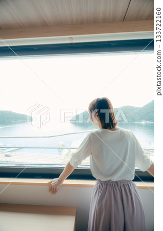 A scene of a woman in her twenties looking at the view from a hotel window A scene of a woman in her twenties looking at the view from a hotel window 133722160