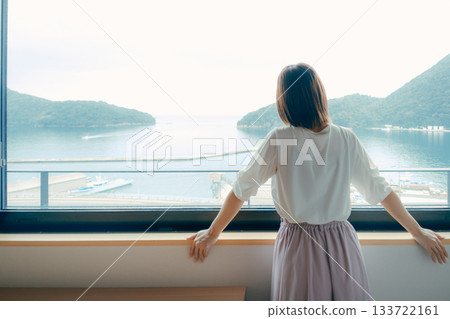 A scene of a woman in her twenties looking at the view from a hotel window A scene of a woman in her twenties looking at the view from a hotel window 133722161