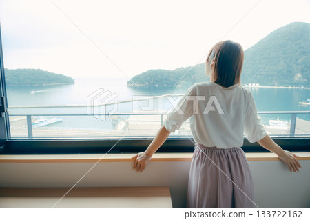 一位二十多歲的女子正望著飯店窗外的景色。 133722162
