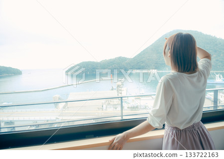 一位二十多歲的女子正望著飯店窗外的景色。 133722163