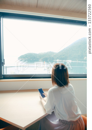 A scene of a woman in her 20s looking at her smartphone in a hotel room 133722560
