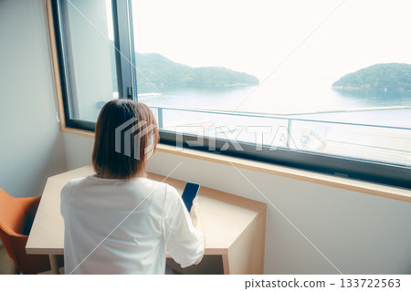 A scene of a woman in her 20s looking at her smartphone in a hotel room 133722563