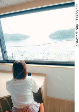 A scene of a woman in her 20s looking at her smartphone in a hotel room 133722565
