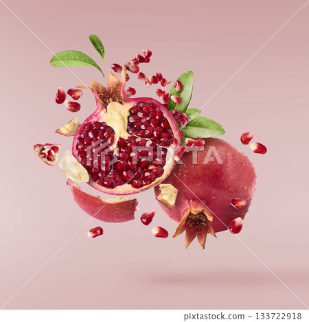 Flying in air fresh ripe whole and cut pomegranate with seeds and leaves isolated. High resolution image 133722918