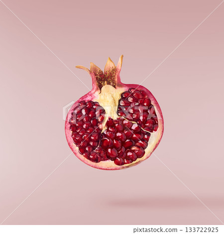 Flying in air fresh ripe whole and cut pomegranate with seeds and leaves isolated. High resolution image Flying in air fresh ripe whole and cut pomegranate with seeds and leaves isolated. High resolution image 133722925
