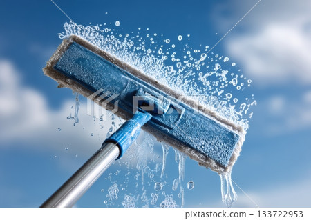 Highspeed shot capturing water arcs during window cleansing scene, Dynamic image showcasing microfiber pad in action against bright sky with sparkling clean glass 133722953