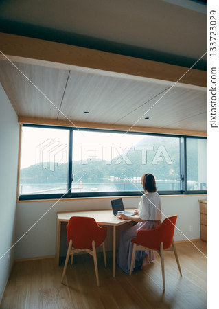A scene of a woman in her twenties working on a computer in a hotel room A scene of a woman in her twenties working on a computer in a hotel room 133723029