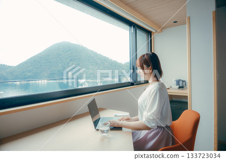 A scene of a woman in her twenties working on a computer in a hotel room 133723034