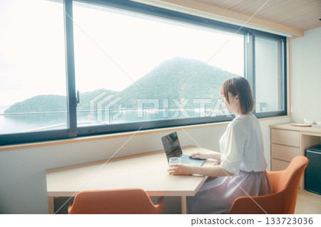 A scene of a woman in her twenties working on a computer in a hotel room 133723036