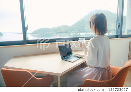 A scene of a woman in her twenties working on a computer in a hotel room 133723037