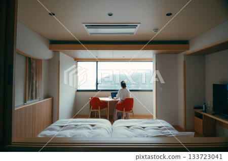 A scene of a woman in her twenties working on a computer in a hotel room A scene of a woman in her twenties working on a computer in a hotel room 133723041