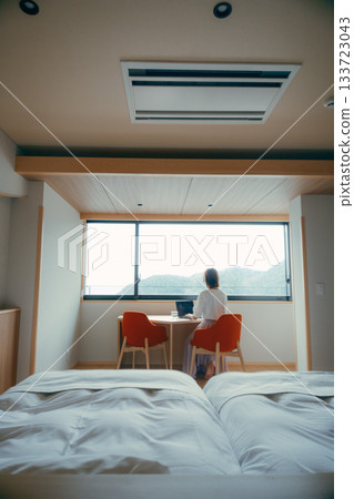 A scene of a woman in her twenties working on a computer in a hotel room A scene of a woman in her twenties working on a computer in a hotel room 133723043