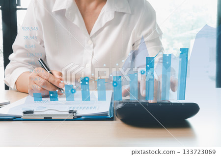Businesswoman analyzing financial reports with digital bar charts and data graphs, representing financial analysis, business growth, investment planning, budget management, strategic decision-making. 133723069