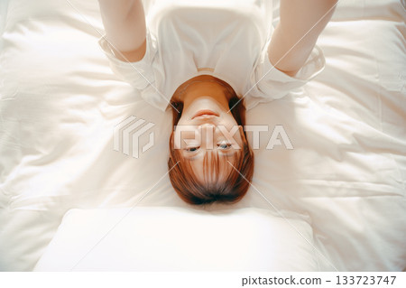 A scene of a woman in her 20s taking a selfie with her smartphone on a hotel bed A scene of a woman in her 20s taking a selfie with her smartphone on a hotel bed 133723747