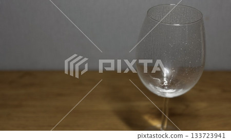 Elegant Clear Wine Glass on Wooden Table with Subtle Reflections Elegant Clear Wine Glass on Wooden Table with Subtle Reflections 133723941