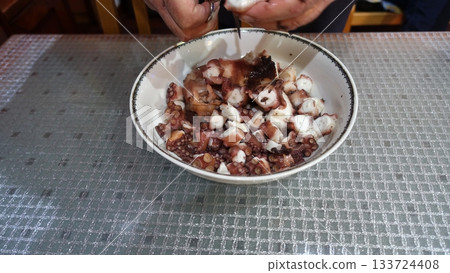 Cutting freshly boiled octopus with scissors to prepare it for the salad. Cutting freshly boiled octopus with scissors to prepare it for the salad. 133724408