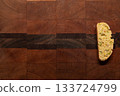 Single, homemade, orange and pistachio holiday biscotti on a wooden cutting board 133724799