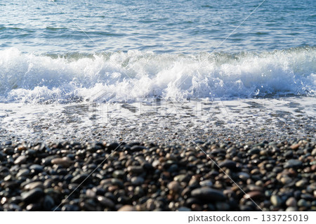 The view captures a stunning seascape with gentle waves lapping on a pebble beach, inviting you to indulge in luxurious spa treatments in a serene atmosphere. 133725019