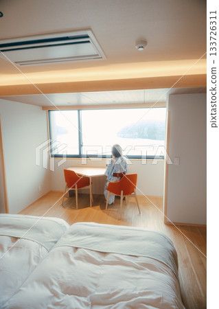 A scene of a woman in her twenties in a yukata standing quietly gazing at the sea 133726311