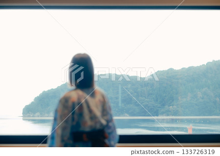 一位二十多歲的女子身穿浴衣，靜靜地凝望著大海。 133726319
