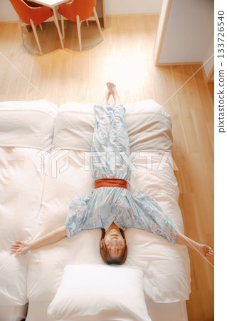 一位身穿浴衣的女子在床上放鬆的場景 133726540