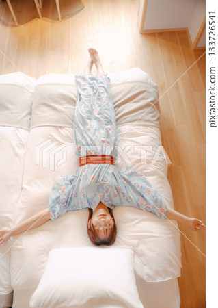 一位身穿浴衣的女子在床上放鬆的場景 133726541