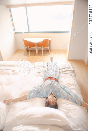 一位身穿浴衣的女子在床上放鬆的場景 133726543