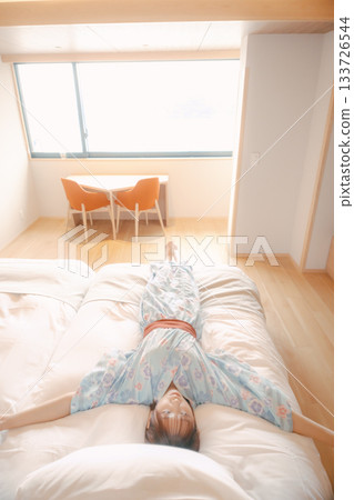 A scene of a woman in a yukata relaxing on a bed 133726544