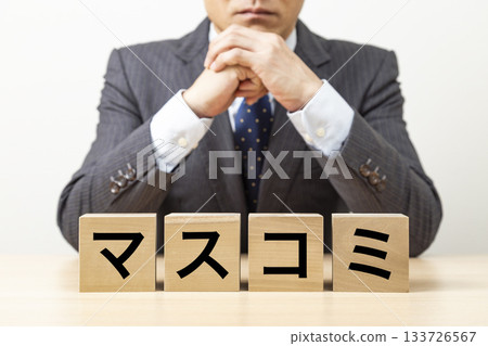 A block with the word "mass media" written on it and a businessman A block with the word "mass media" written on it and a businessman 133726567