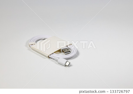 New white USB type charger cable in paper pack, compatible for many devices, wrapped in a spiral shape, isolated on white background. New white USB type charger cable in paper pack, compatible for many devices, wrapped in a spiral shape, isolated on white background. 133726797